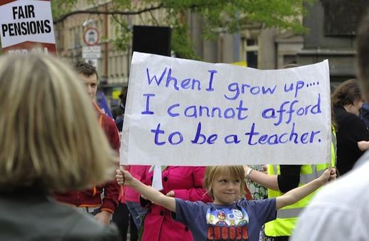 Image of a crowd at a rally to support teachers with the focus on a young girl holding up a sign that reads: 